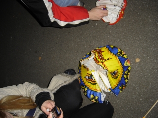 Susi h�lt ihr Handy in der Hand und kniet �ber ihrer Laterne