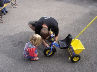 Dominic bastelt am Dreirad von Meike, die zuschaut